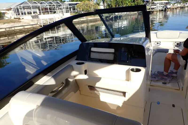  Yacht Photos Pics 2021 Scout 277 Dorado boat interior with seating and dashboard, docked by a waterfront.