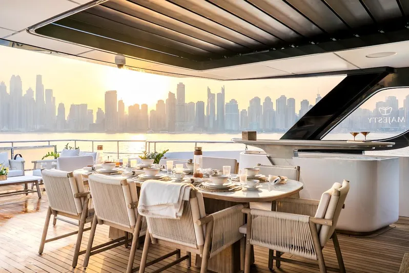  Yacht Photos Pics Luxurious 2025 Majesty 100 Terrace yacht with elegant dining setup and city skyline view.