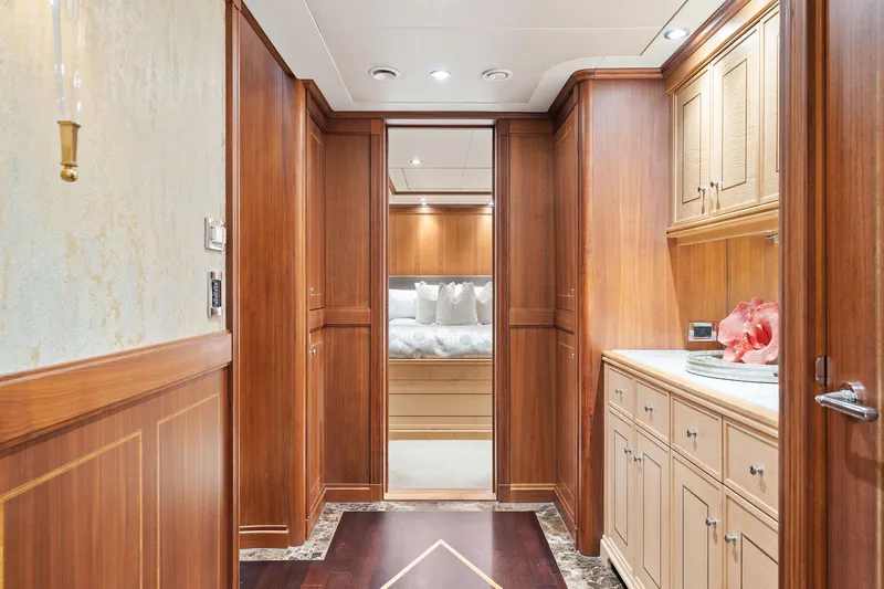 Invictus Yacht Photos Pics Luxurious wood-paneled hallway in 2006 Palmer Johnson motor yacht, featuring elegant cabinetry and plush bedding.