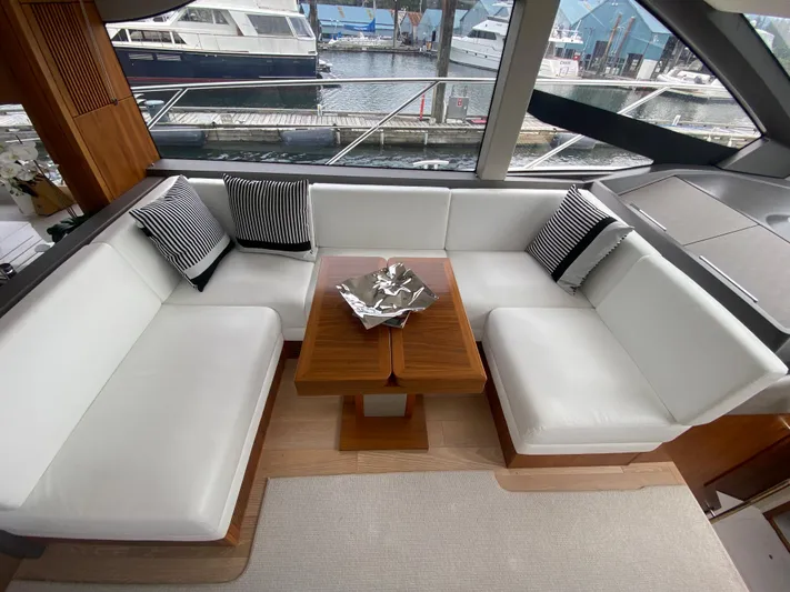 Sea Sea V Yacht Photos Pics Luxurious Sunseeker Manhattan 52 yacht interior with white seating and striped cushions, docked at marina.