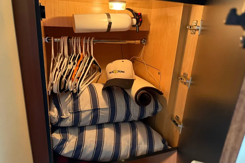Turn The Page Yacht Photos Pics Cabinet in 2006 Sea Ray 48 Sundancer with hangers, striped pillows, and a cap.