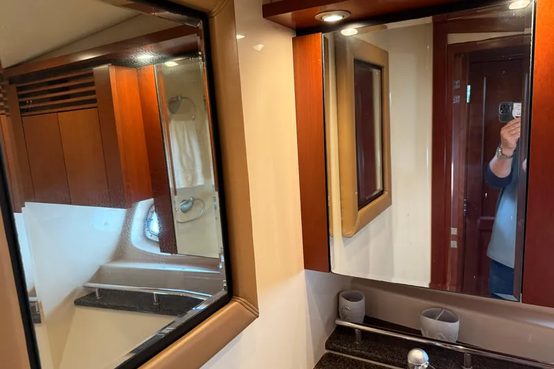 Turn The Page Yacht Photos Pics Luxurious bathroom interior of 2006 Sea Ray 48 Sundancer yacht with wood accents and mirrors.