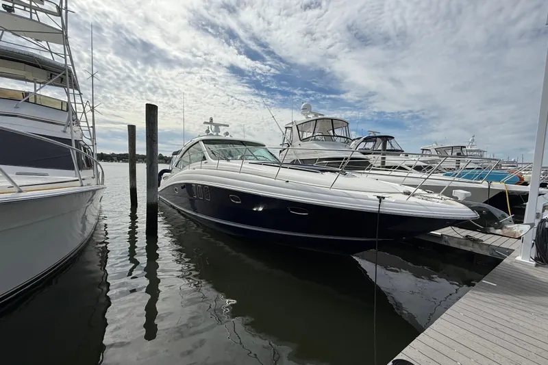 Turn The Page Yacht Photos Pics 2006 Sea Ray 48 Sundancer yacht docked at marina under cloudy sky.