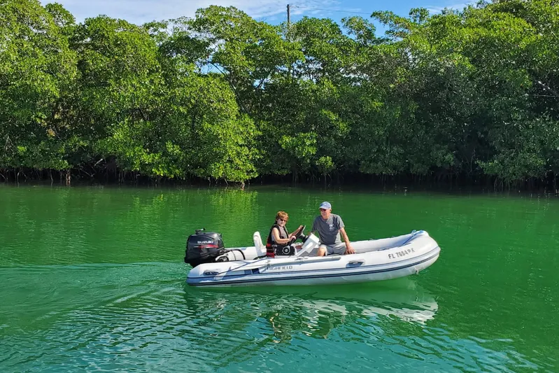 Turn The Page Yacht Photos Pics Two people in a small boat on green water near lush mangroves.
