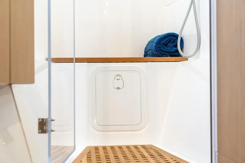 Superlux Yacht Photos Pics 2023 Aquila 42 Yacht interior shower with wooden accents and blue towel.