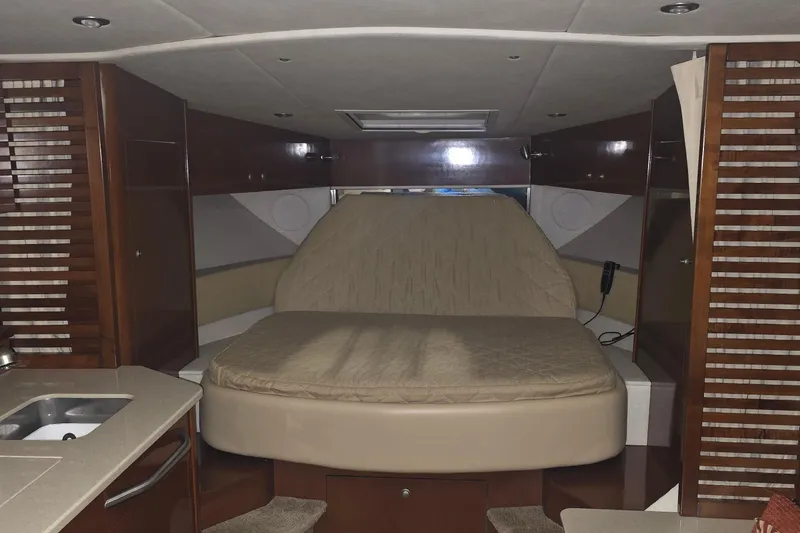Lucky 13 Yacht Photos Pics 2009 Sea Ray Sundancer 350 cabin interior with bed, wood paneling, and kitchenette.