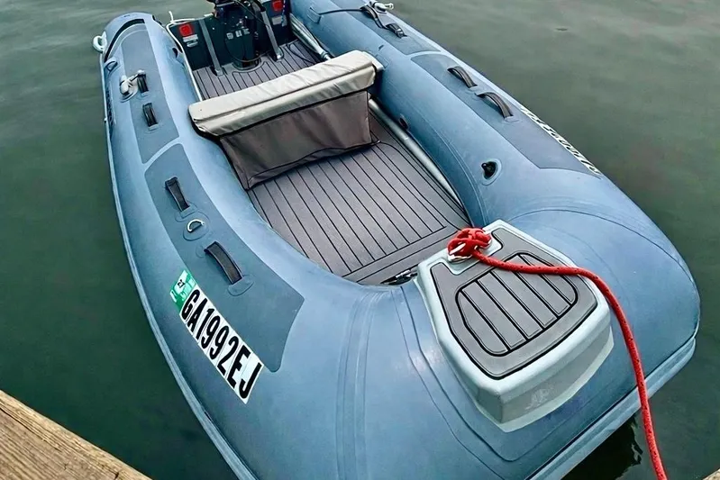 Cecil Yacht Photos Pics Blue inflatable boat docked with red rope, featuring a comfortable seating area.