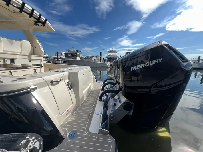  Yacht Photos Pics 2025 Scout 425 LXF boat with Mercury outboard engine at marina under blue sky.