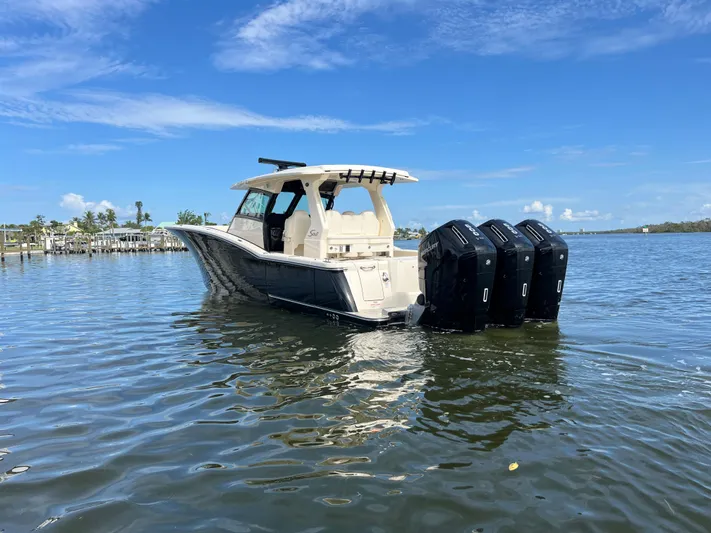 Yacht Photos Pics 2025 Scout 425 LXF boat with triple engines on calm water under blue sky.