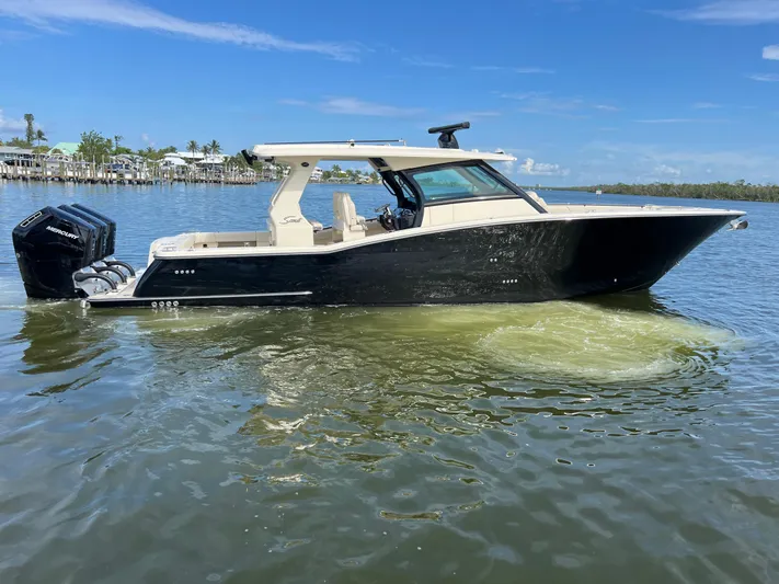  Yacht Photos Pics 2025 Scout 425 LXF boat on calm water, featuring sleek design and powerful Mercury engines.