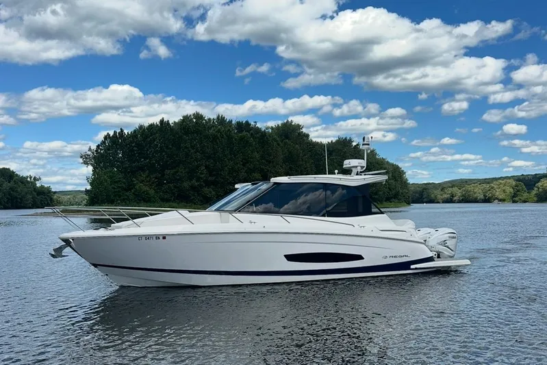  Yacht Photos Pics 2022 Regal 36 XO boat on a serene lake with lush green trees.