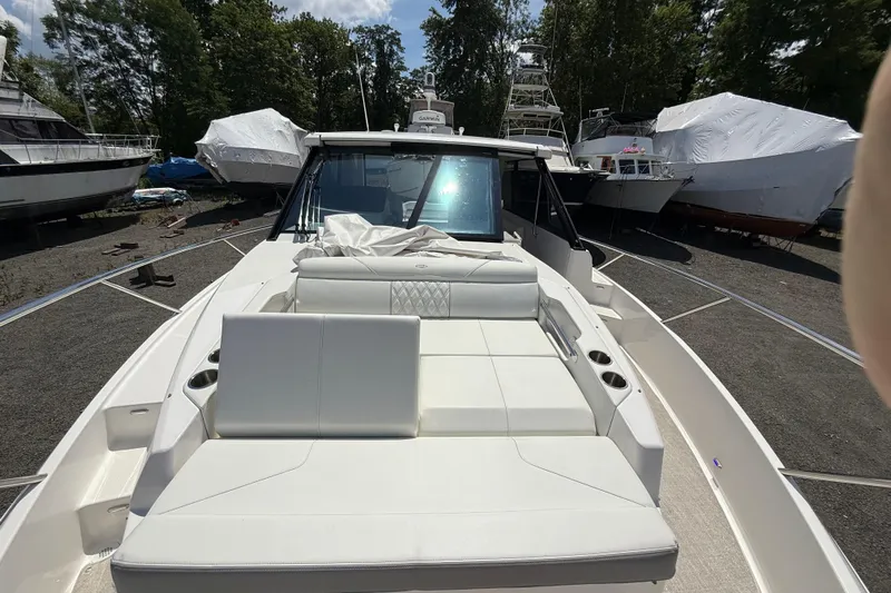  Yacht Photos Pics 2022 Regal 36 XO boat with white seating, docked outdoors among other vessels.