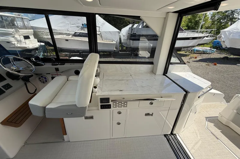  Yacht Photos Pics 2022 Regal 36 XO yacht interior with helm, seating, and cabinetry in a marina setting.