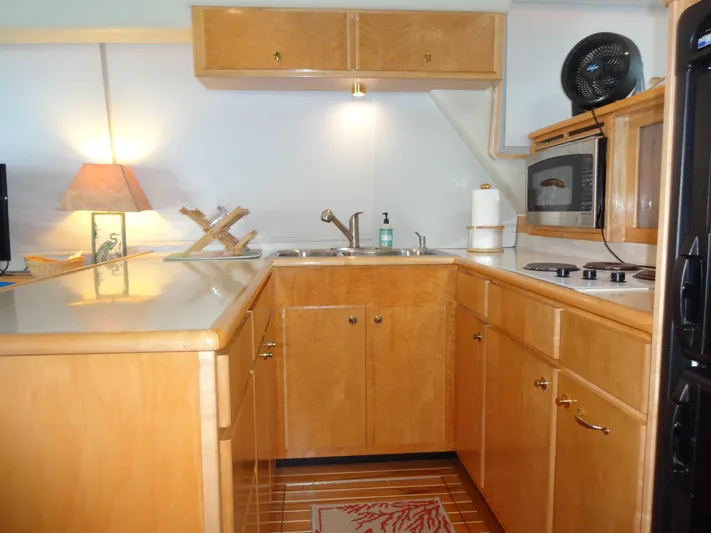 Gypsy Soul Yacht Photos Pics 1998 Navigator 53 Classic yacht kitchen with wooden cabinets, sink, microwave, and stovetop.