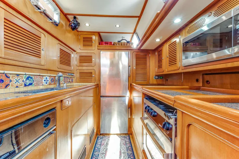 Perfect Symmetry Yacht Photos Pics Luxurious 2006 Hylas 70 yacht kitchen with wood cabinetry and modern appliances.