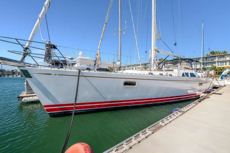 Perfect Symmetry Yacht Photos Pics Hylas 70 sailboat from 2006 docked in a marina, featuring sleek design and red stripe.