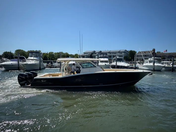  Yacht Photos Pics 2018 Scout 380 LXF boat cruising in a marina with other boats docked nearby.