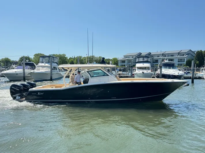  Yacht Photos Pics 2018 Scout 380 LXF boat cruising in a marina with other boats docked nearby.