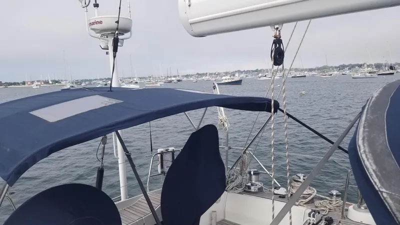  Yacht Photos Pics Sailing yacht CNB 64, 2003 model, with blue canopy, anchored in a busy harbor.