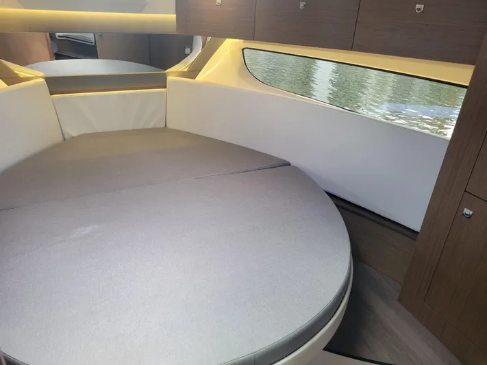  Yacht Photos Pics 2020 Jeanneau NC1095 cabin interior with round bed and window view.