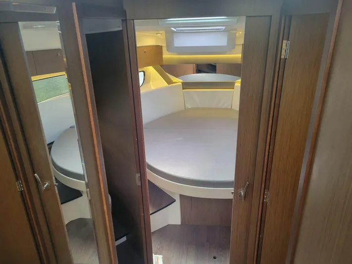  Yacht Photos Pics Interior cabin of 2020 Jeanneau NC1095 boat with round bed and wooden finish.