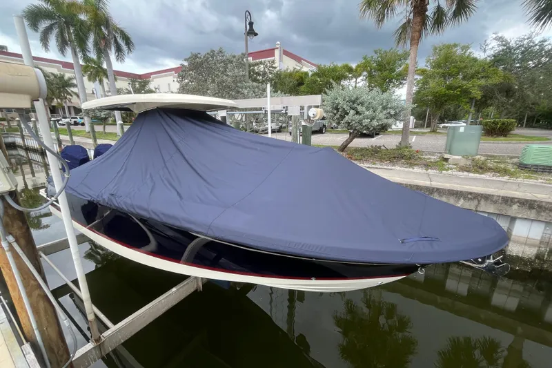  Yacht Photos Pics 2025 Chris-Craft Catalina 28 boat covered, docked near palm trees and buildings.