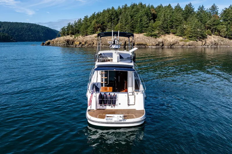 Endeavour Yacht Photos Pics Nimbus 405 Flybridge 2023 yacht on serene water near forested island.