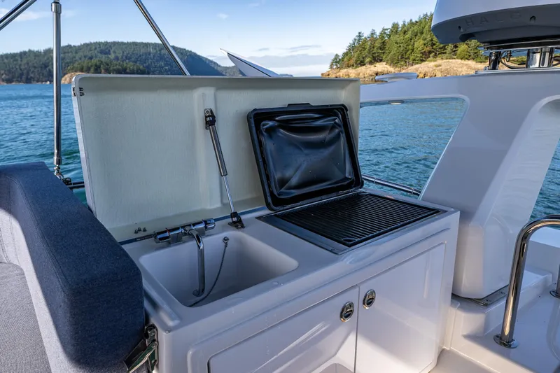 Endeavour Yacht Photos Pics Outdoor kitchen on 2023 Nimbus 405 Flybridge yacht with sink and grill, scenic ocean view.