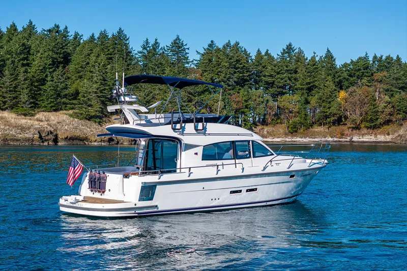 Endeavour Yacht Photos Pics 2023 Nimbus 405 Flybridge yacht cruising on a serene lake with forested shoreline.