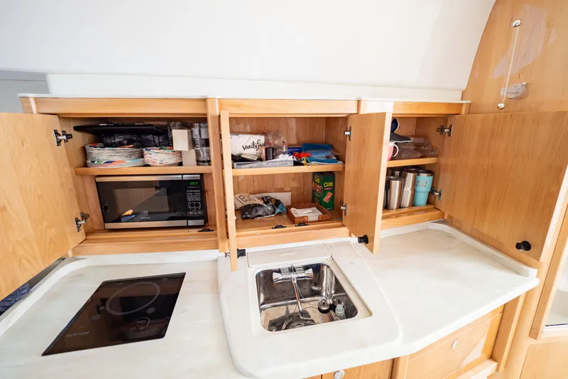  Yacht Photos Pics 2018 Intrepid 475 Sport Yacht kitchen with microwave, sink, and wooden cabinets.