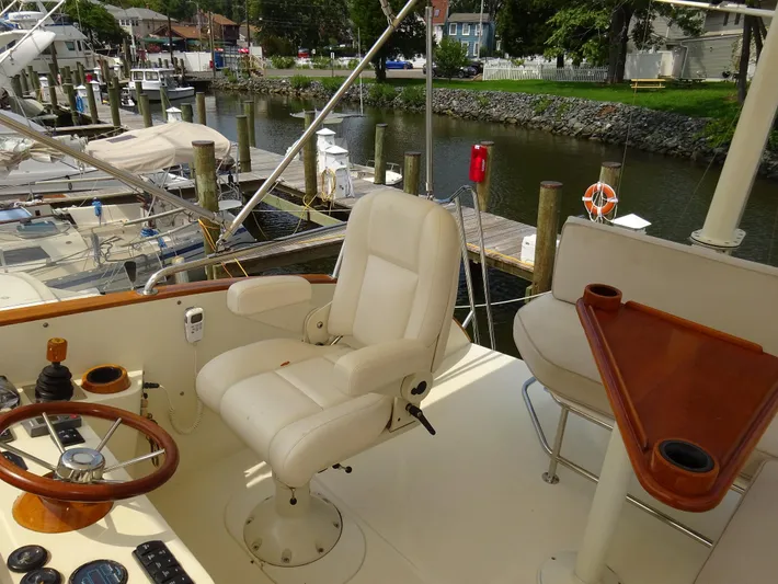Fine Time Yacht Photos Pics Captain's chair and helm on 2002 Hinckley Talaria 44 FB yacht, docked by a serene marina.