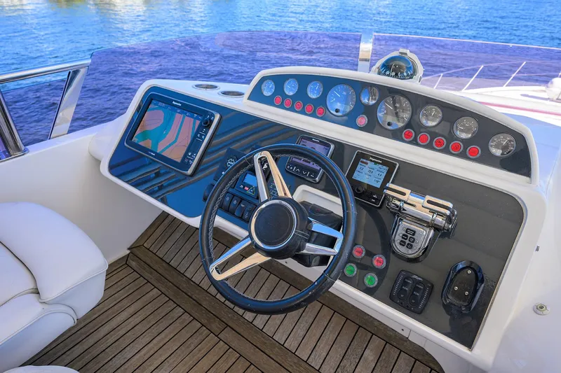 Tight Squeeze Yacht Photos Pics Cockpit of 2016 Princess F64 yacht with navigation controls and steering wheel, overlooking water.