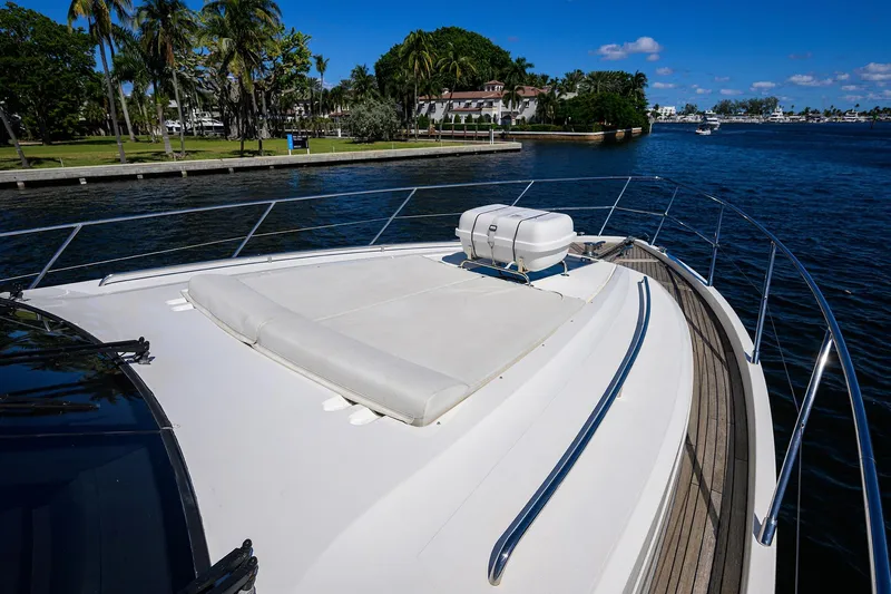 Tight Squeeze Yacht Photos Pics Bow view of 2016 Princess F64 yacht, featuring sunbathing area and scenic waterfront.