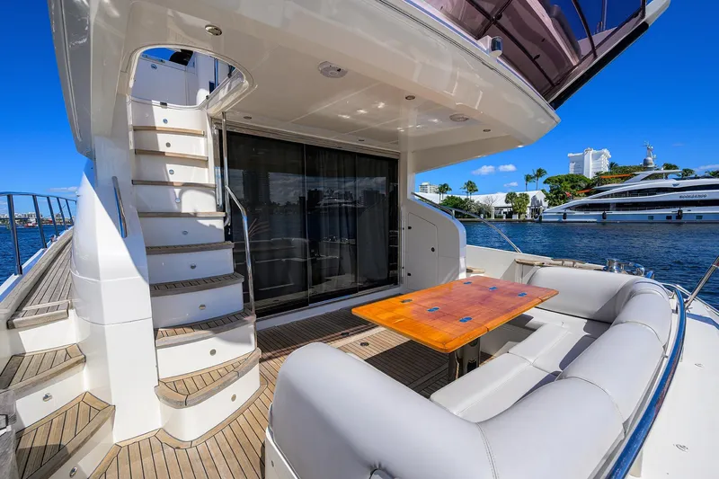 Tight Squeeze Yacht Photos Pics Luxurious 2016 Princess F64 yacht deck with seating, table, and staircase, docked by waterfront.