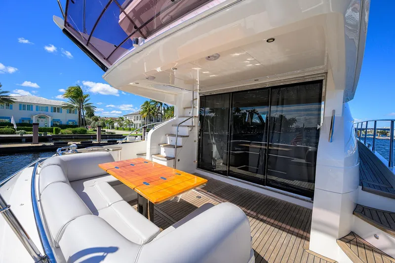 Tight Squeeze Yacht Photos Pics Luxurious 2016 Princess F64 yacht deck with seating and table, docked by waterfront homes.