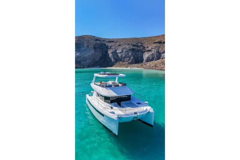 Mabinti Yacht Photos Pics 2024 Leopard 40 Powercat in turquoise waters near rocky coastline.