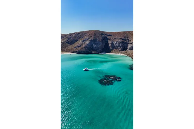 Mabinti Yacht Photos Pics 2024 Leopard 40 Powercat cruising in a serene turquoise bay with rocky cliffs.