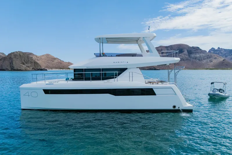 Mabinti Yacht Photos Pics 2024 Leopard 40 Powercat yacht on serene blue water with rocky coastline backdrop.