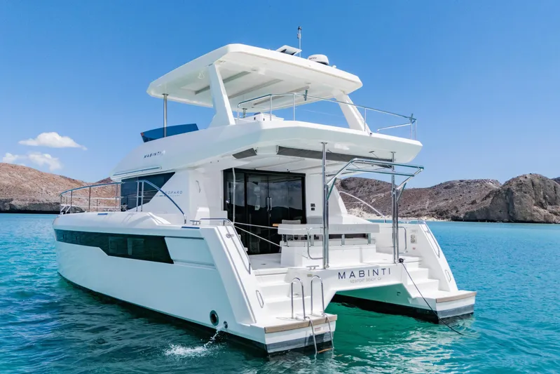 Mabinti Yacht Photos Pics 2024 Leopard 40 Powercat yacht on turquoise water, clear sky, rocky coastline backdrop.