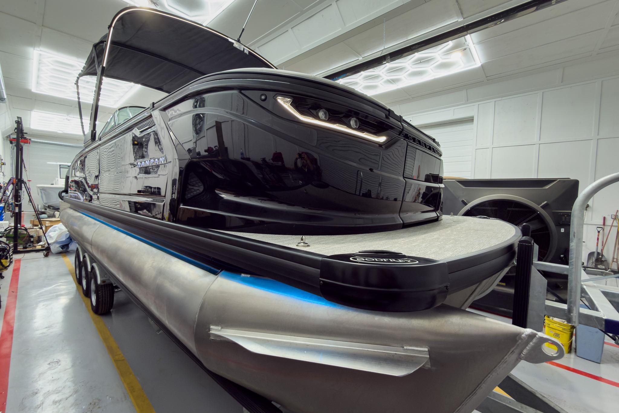 2026 Godfrey Sanpan 27' Tritoon boat in a workshop, showcasing sleek design and modern features.