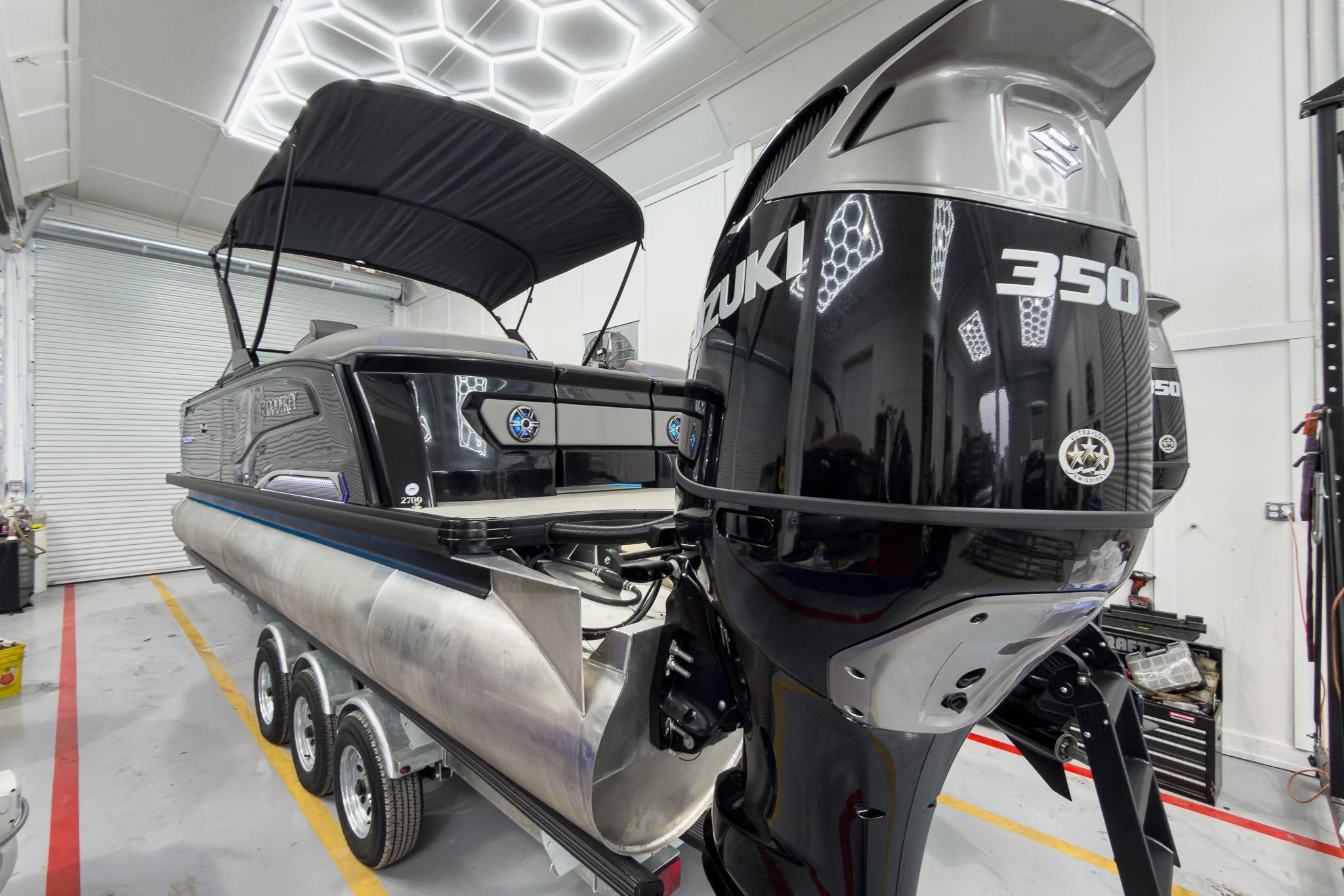 2026 Godfrey Sanpan 27' Tritoon with Suzuki 350 engine in a garage setting.