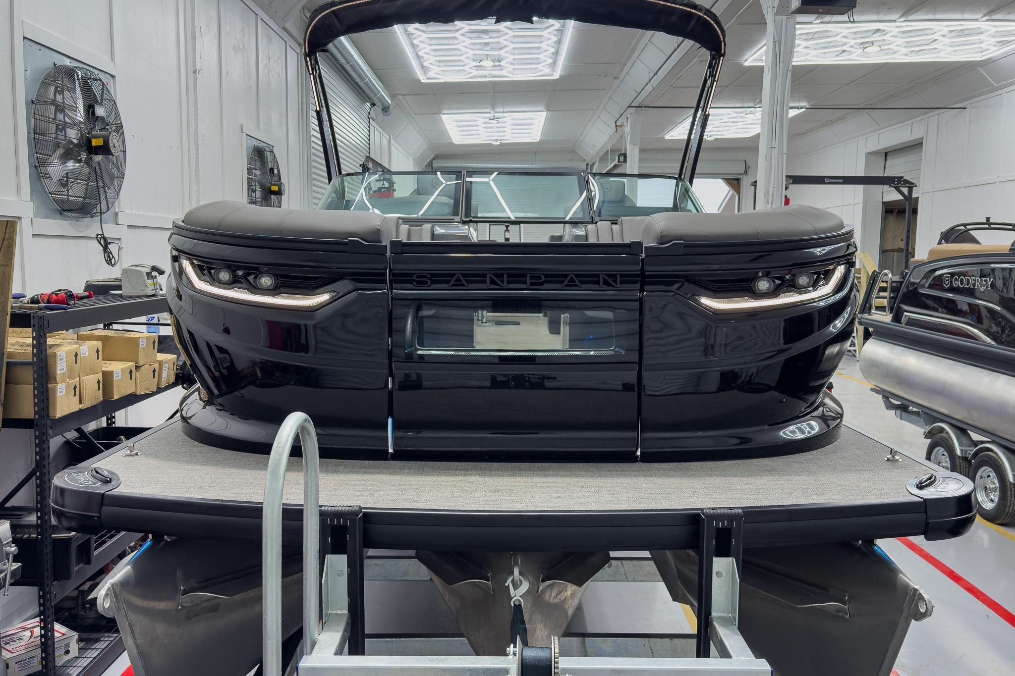 2026 Godfrey Sanpan 27' Tritoon in showroom, featuring sleek black design and modern amenities.