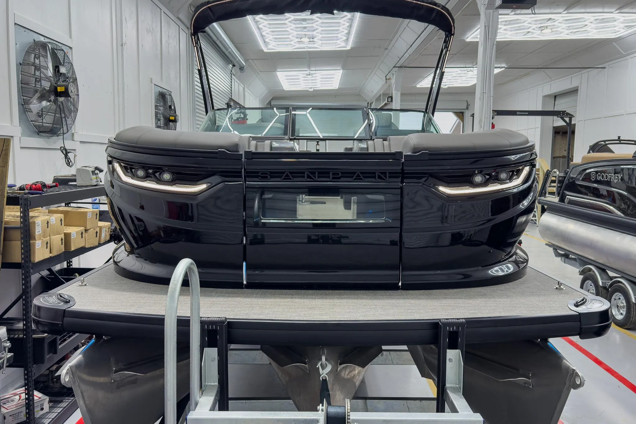 2026 Godfrey Sanpan 27' Tritoon in showroom, featuring sleek black design and modern amenities.