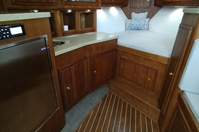 Never Enough Yacht Photos Pics 2017 Out Island SeaTek 36 Express cabin with wood cabinetry and compact kitchenette.