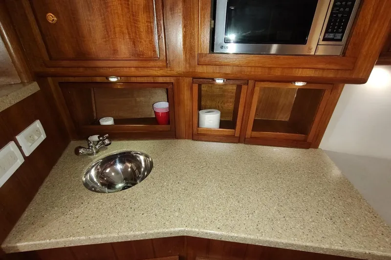 Never Enough Yacht Photos Pics 2017 Out Island SeaTek 36 Express interior with sink, microwave, and wooden cabinetry.