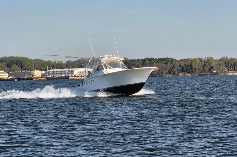 Never Enough Yacht Photos Pics 2017 Out Island SeaTek 36 Express cruising on a calm lake with trees in the background.