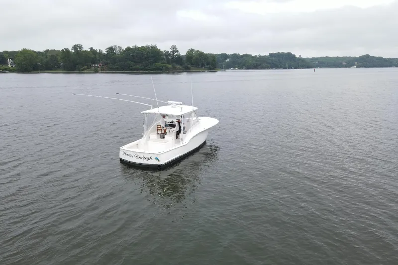Never Enough Yacht Photos Pics 2017 Out Island SeaTek 36 Express boat on calm water, surrounded by lush greenery.