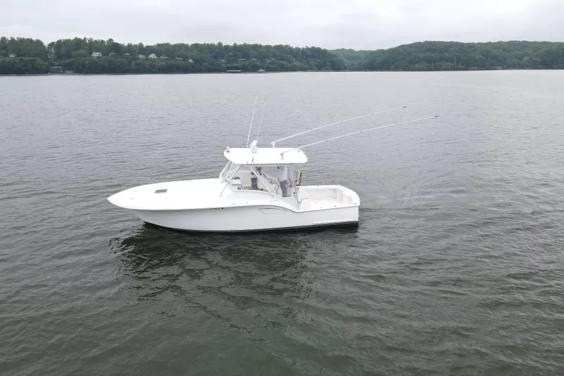 Never Enough Yacht Photos Pics 2017 Out Island SeaTek 36 Express boat on calm water, surrounded by lush greenery.