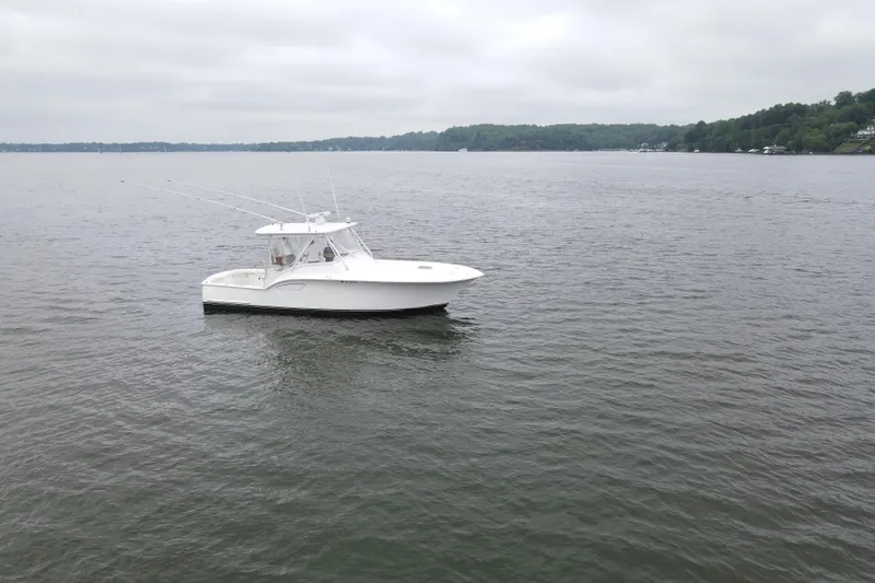 Never Enough Yacht Photos Pics 2017 Out Island SeaTek 36 Express boat on calm lake under cloudy sky.
