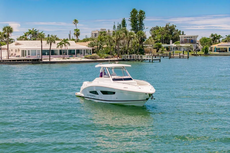  Yacht Photos Pics 2024 Regal 33 SAV boat on serene water near luxury waterfront homes.